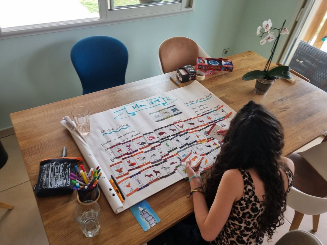 Une jeune personne compose son tableau « Mon rêve » avec des cartes illustrées