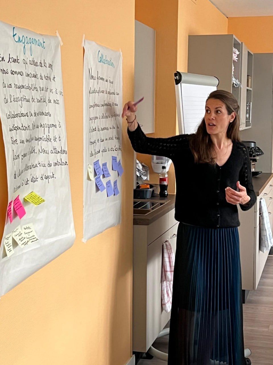 Nathalie présente des affiches sur l'engagement et la collaboration, couvertes de post-it